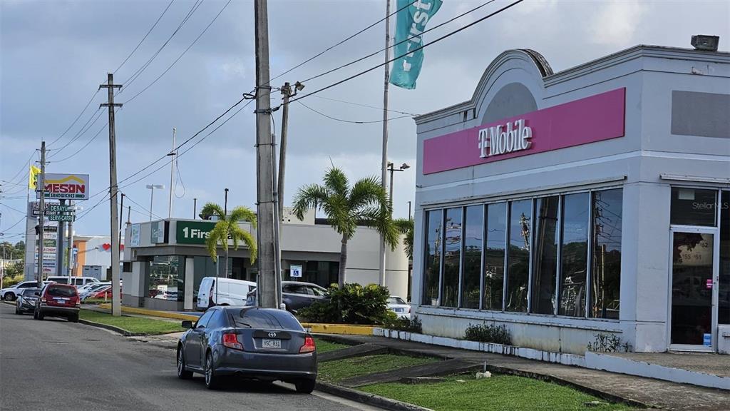 A T-Mobile store and a FirstBank branch stand along a street with parked cars — Km 40.5 PR 3, FAJARDO, PR