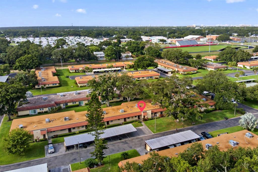 An aerial view shows a residential complex with multiple single-story buildings and covered parking areas — 1701 PINEHURST ROAD UNIT 23G, DUNEDIN, FL