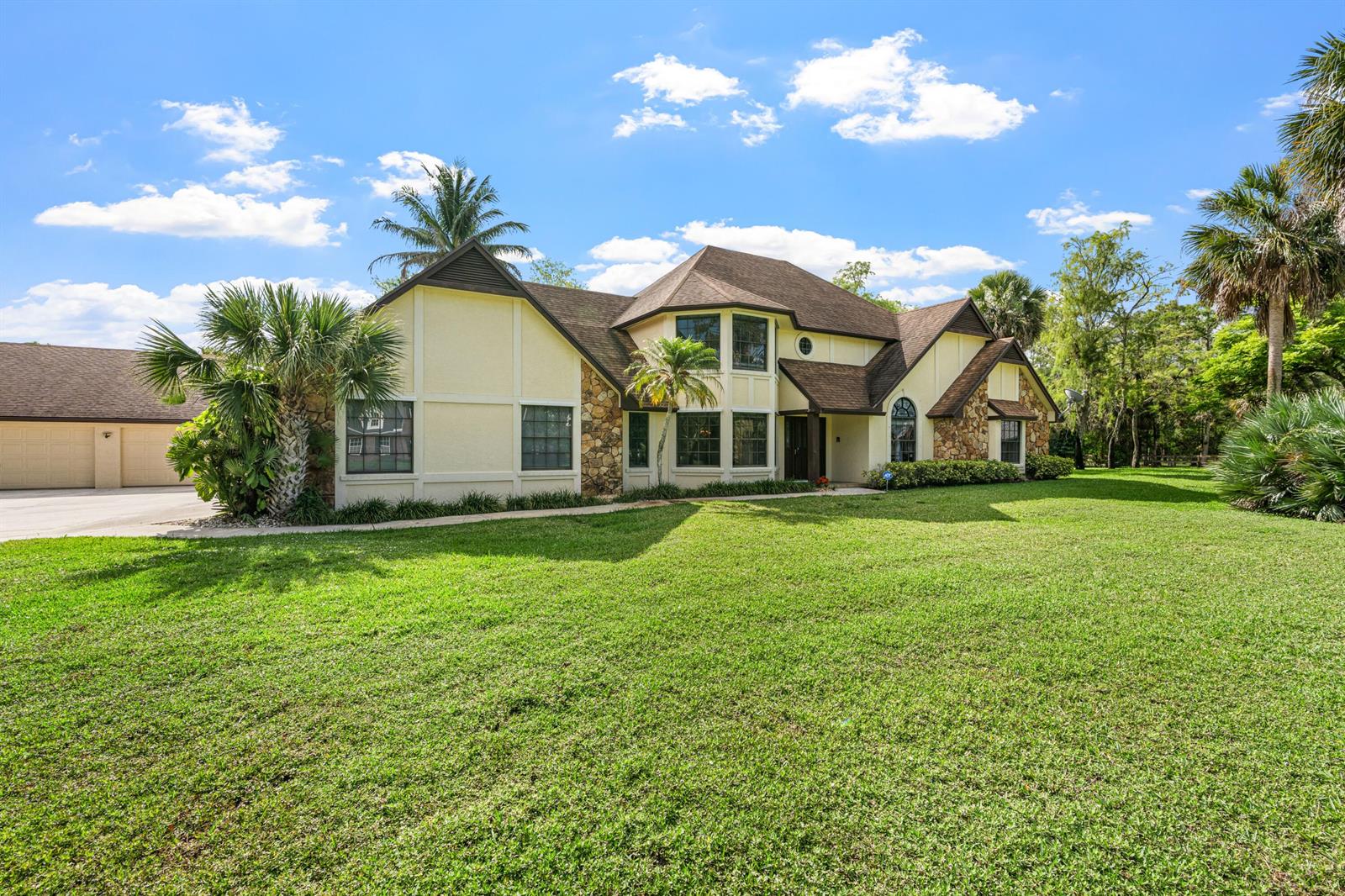 A two-story house with a beige exterior, stone accents, and a large front lawn — 3693 Valley Park Way, Lake Worth FL 33467, LAKE WORTH, FL