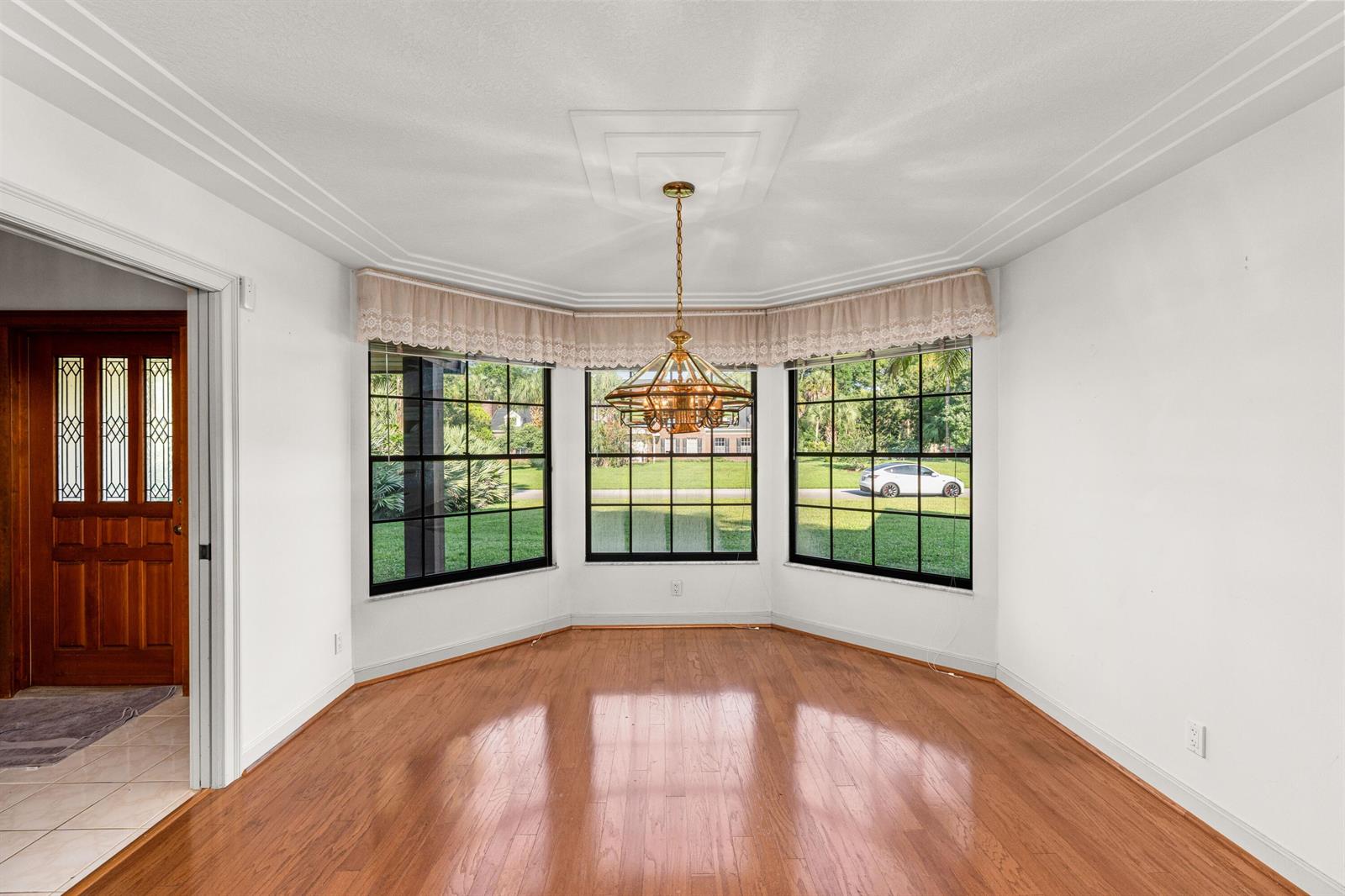 An empty dining room with hardwood floors, a bay window, and a brass chandelier — 3693 Valley Park Way, Lake Worth FL 33467, LAKE WORTH, FL