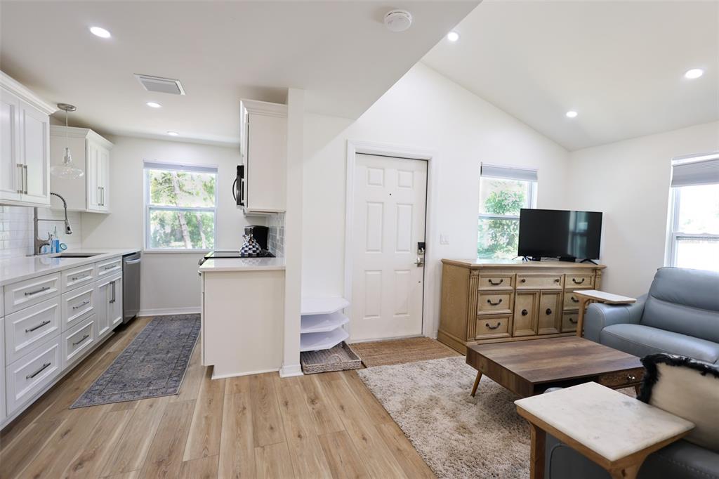 A bright open-concept kitchen and living area with white cabinets and light wood flooring — 4501 70TH STREET N, ST PETERSBURG, FL