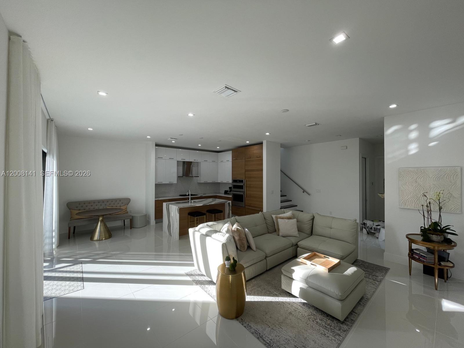 A bright open-concept living room and kitchen featuring white tile floors and modern cabinetry — 8283 NW 44th St, Doral FL 33166, DORAL, FL