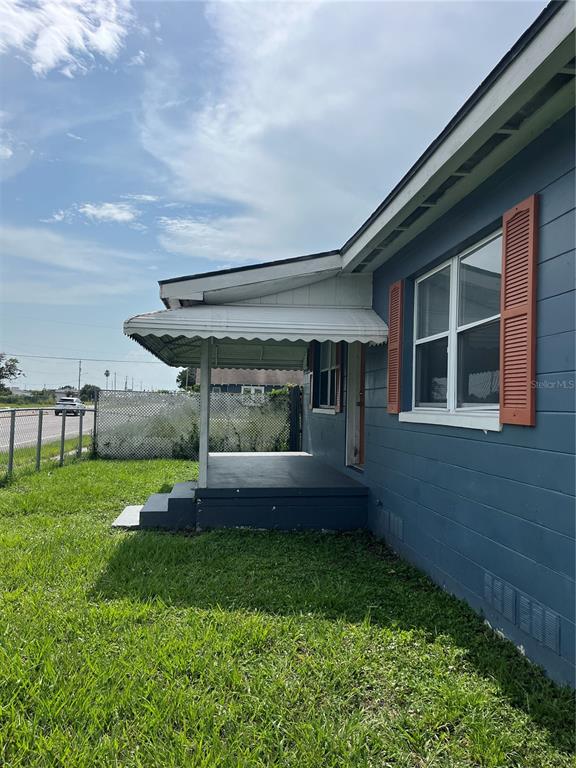 A blue house exterior features a covered porch with a white awning and orange shutters — 1206 E CANAL STREET, MULBERRY, FL