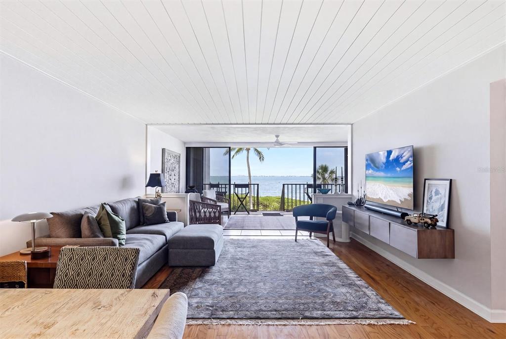 A living room features tile floors, a large area rug, and sliding doors overlooking water — 3460 WILD OAK BAY BOULEVARD UNIT 143, BRADENTON, FL