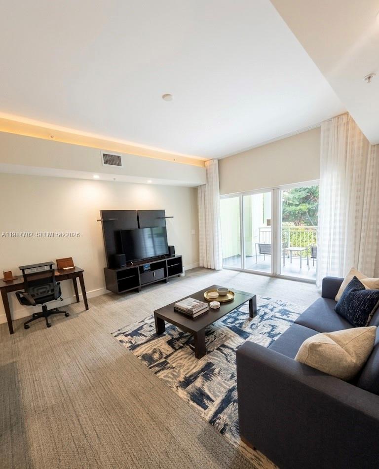 A living room features a dark wood entertainment center, a desk, and a balcony view — 5300 NW 87th Ave # 1109, Doral FL 33178, DORAL, FL