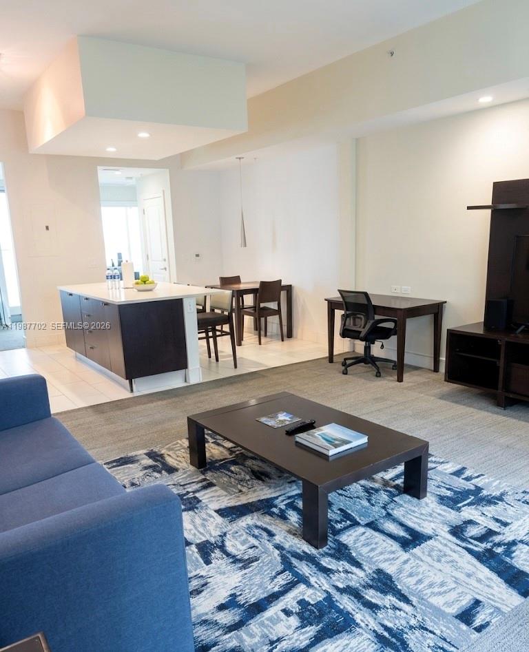 A living room with a blue sofa, coffee table, desk, and an adjacent kitchen island — 5300 NW 87th Ave # 1109, Doral FL 33178, DORAL, FL