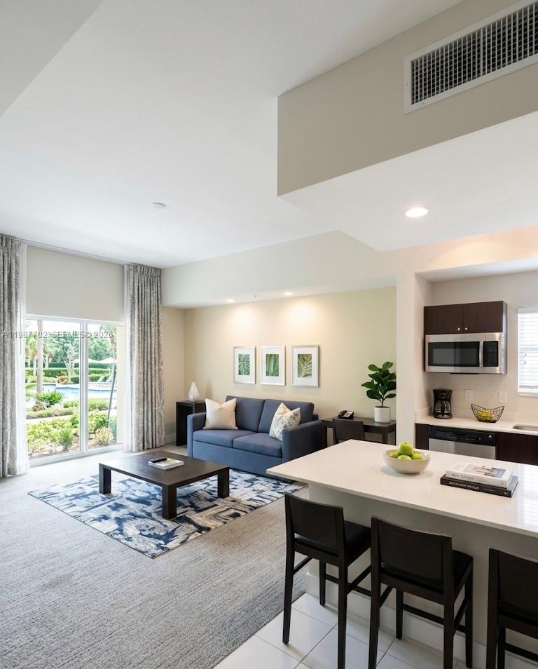 A living room and kitchen area with a blue sofa, coffee table, and breakfast bar — 5300 NW 87th Ave # 1109, Doral FL 33178, DORAL, FL
