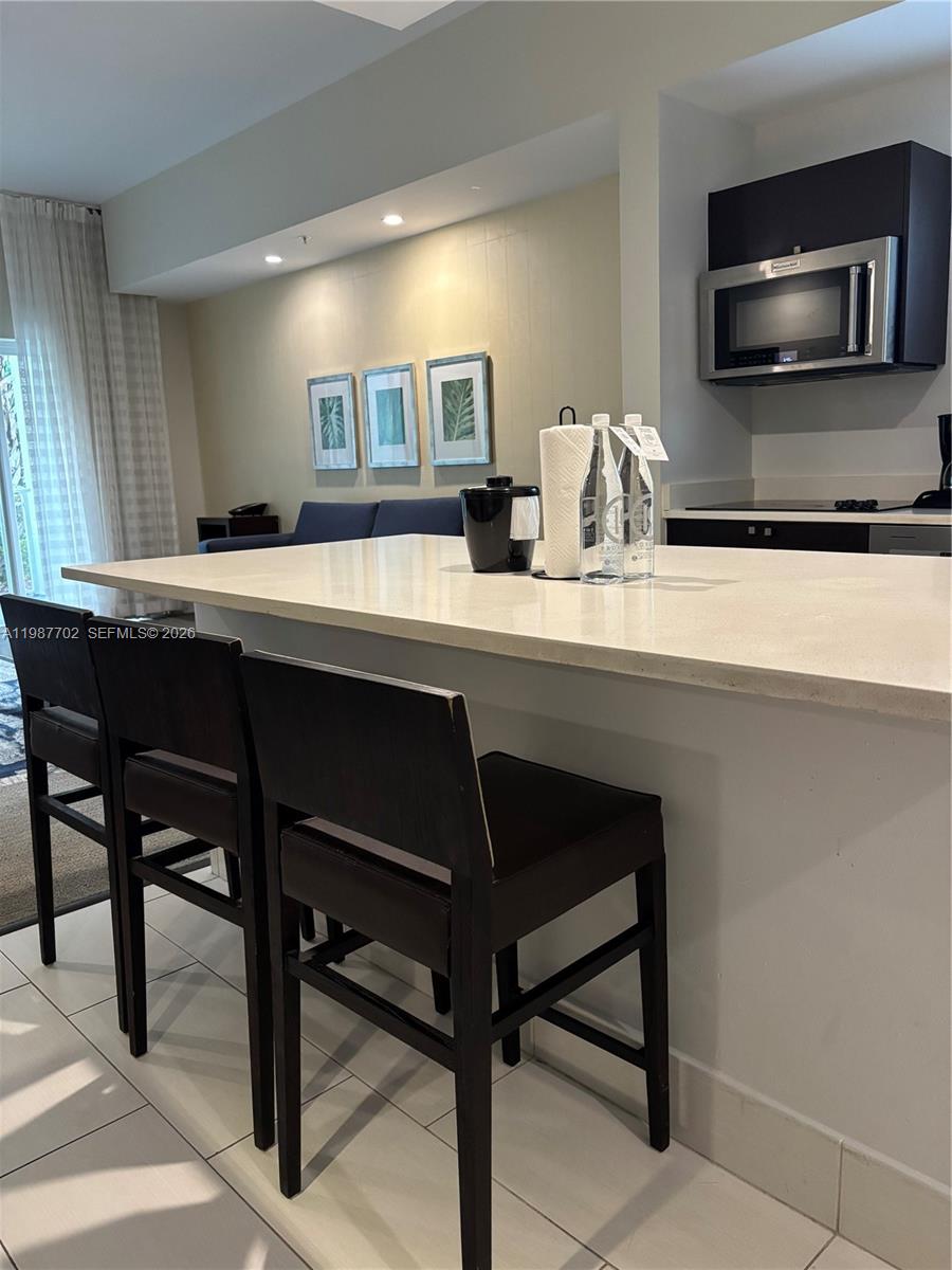 A kitchen island with three dark wooden bar stools sits in front of a kitchen — 5300 NW 87th Ave # 1109, Doral FL 33178, DORAL, FL