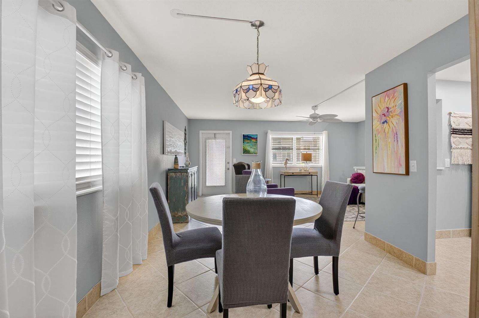 A dining area with a round table and grey chairs sits before a living room — 499 Monaco K # K, Delray Beach FL 33446, DELRAY BEACH, FL