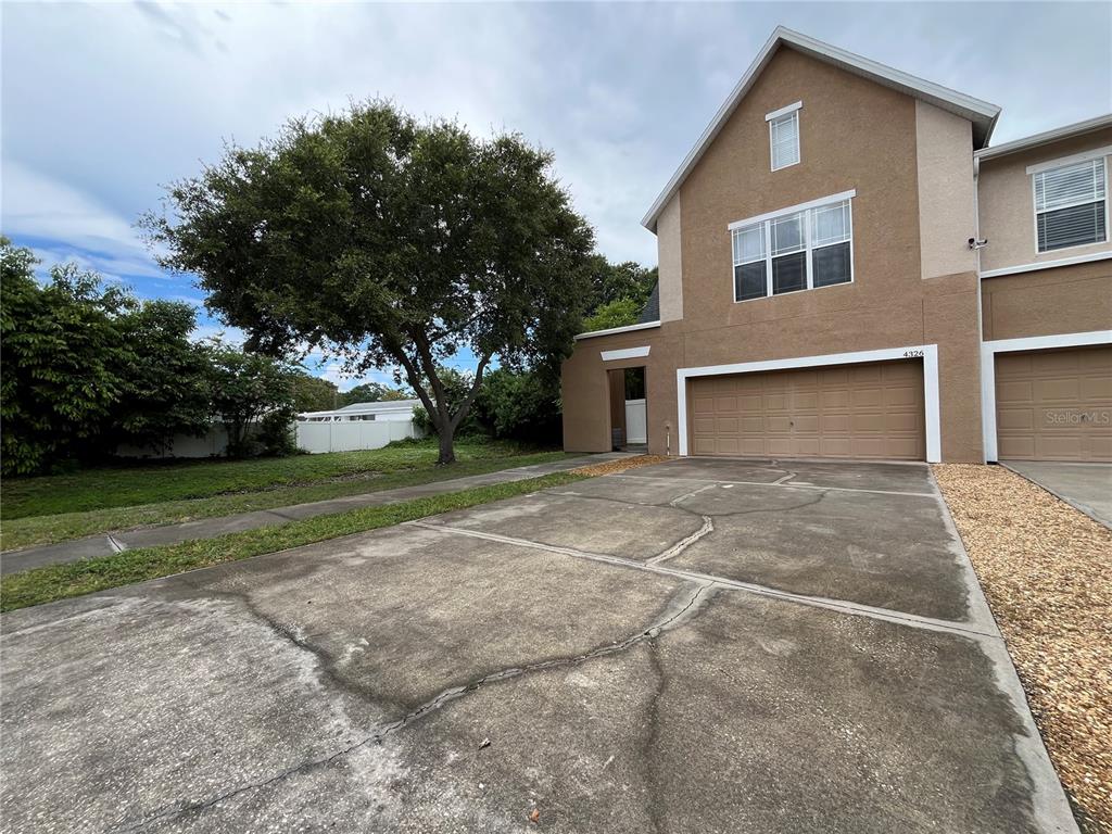 A two-story tan stucco townhouse with a concrete driveway and an attached two-car garage — 4326 TYLER CIRCLE N, ST PETERSBURG, FL
