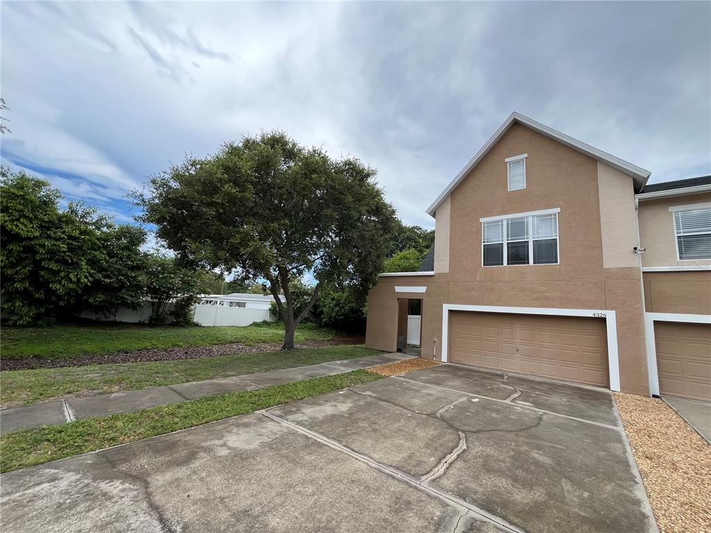 A tan two-story townhouse with a two-car garage and a large tree in the yard — 4326 TYLER CIRCLE N, ST PETERSBURG, FL