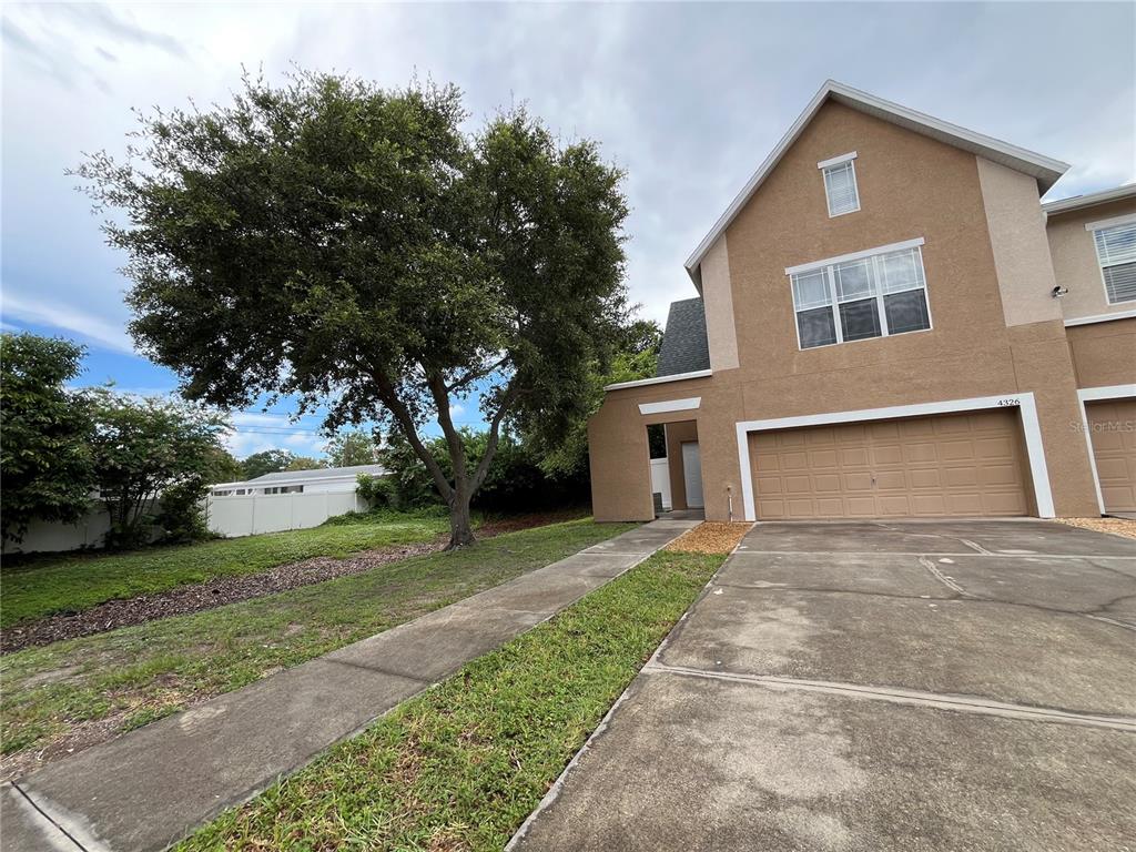 A two-story tan stucco townhouse with a two-car garage and a large tree — 4326 TYLER CIRCLE N, ST PETERSBURG, FL