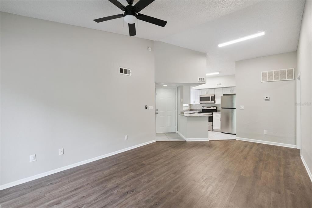 An open-concept living area with wood-look flooring, a ceiling fan, and an adjacent kitchen — 1948 LAKE ATRIUMS CIRCLE UNIT 124, ORLANDO, FL