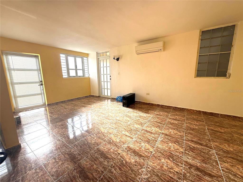 An empty room with brown patterned tile flooring, white walls, and multiple windows and doors — DD42 A LUQUILLO MAR, LUQUILLO, PR