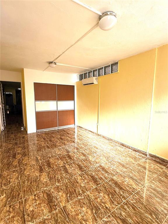 An empty room features brown tiled floors, a sliding closet, and a wall-mounted air conditioner — DD42 A LUQUILLO MAR, LUQUILLO, PR