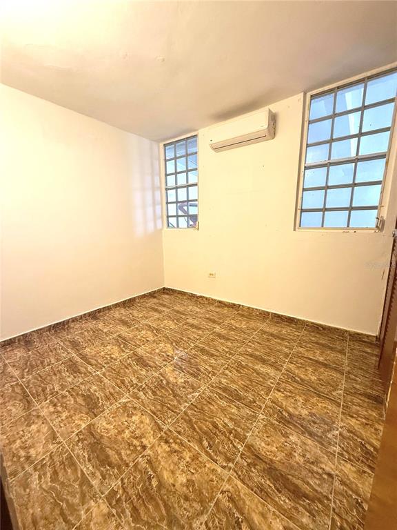 An empty room features brown marble-patterned tile flooring, white walls, and a wall-mounted air conditioner — DD42 A LUQUILLO MAR, LUQUILLO, PR