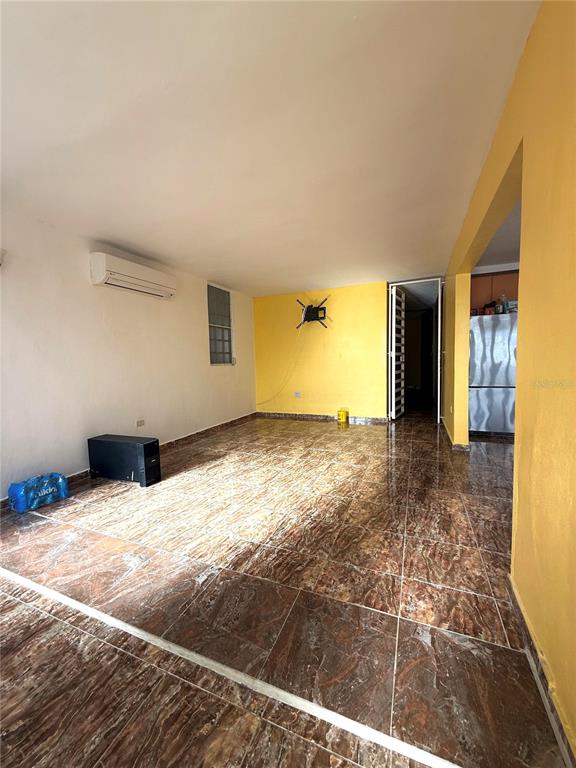 An empty room features brown marble-patterned tile flooring, yellow accent walls, and a wall-mounted air conditioner — DD42 A LUQUILLO MAR, LUQUILLO, PR