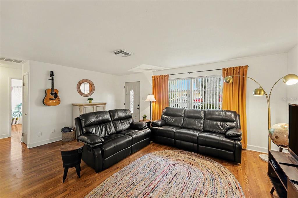 A living room features two black leather sofas, a round rug, and a guitar wall-mounted — 1251 OAKVIEW AVENUE, CLEARWATER, FL