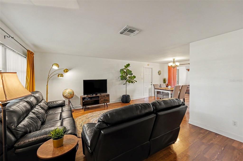 A living room with black leather sofas, a television console, and an adjacent dining area — 1251 OAKVIEW AVENUE, CLEARWATER, FL