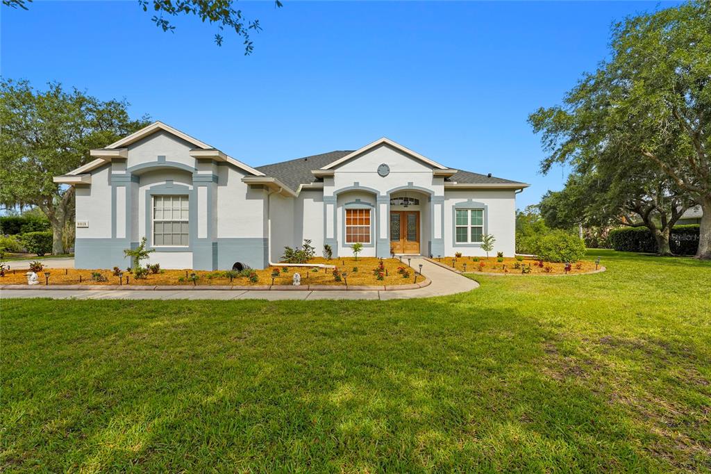 A single-story house with a light-colored stucco exterior, a gray roof, and a front walkway — 8018 SNOWY EGRET PLACE, BRADENTON, FL