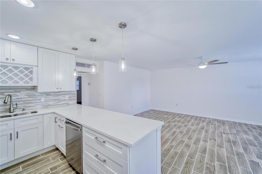 A modern kitchen with white cabinets and a peninsula overlooks an open-concept living area — 202 BEDFORD TRAIL UNIT 97, SUN CITY CENTER, FL