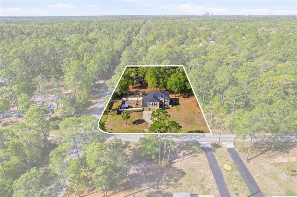 An aerial view shows a house with a fenced yard surrounded by dense forest — 9508 N DAWNFLOWER AVENUE, CRYSTAL RIVER, FL