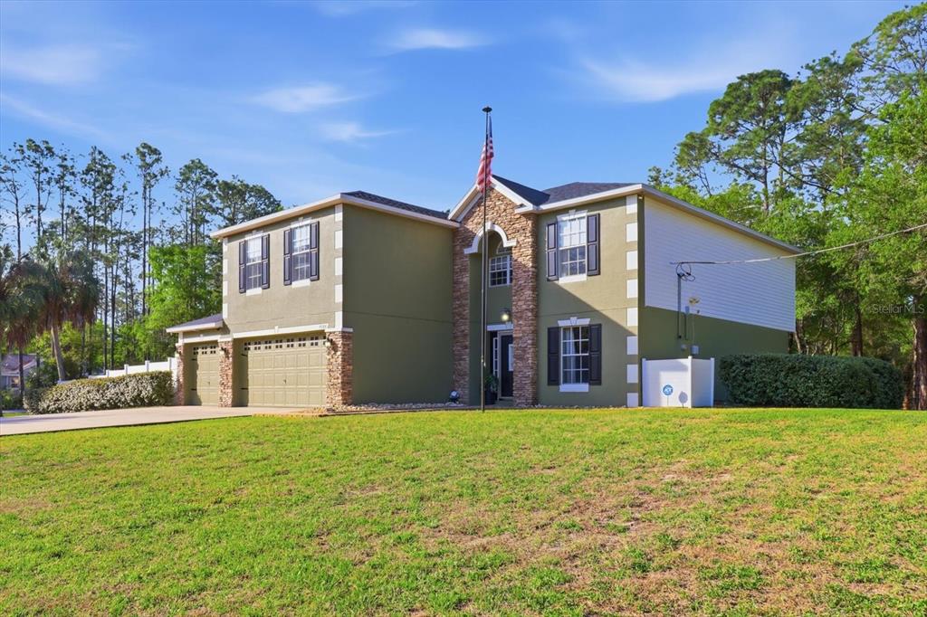 A two-story house with a green exterior, stone accents, and a two-car garage — 9508 N DAWNFLOWER AVENUE, CRYSTAL RIVER, FL