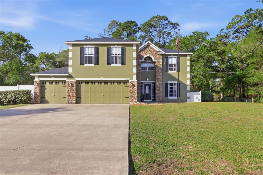 A two-story house with green siding, stone accents, and a three-car garage — 9508 N DAWNFLOWER AVENUE, CRYSTAL RIVER, FL