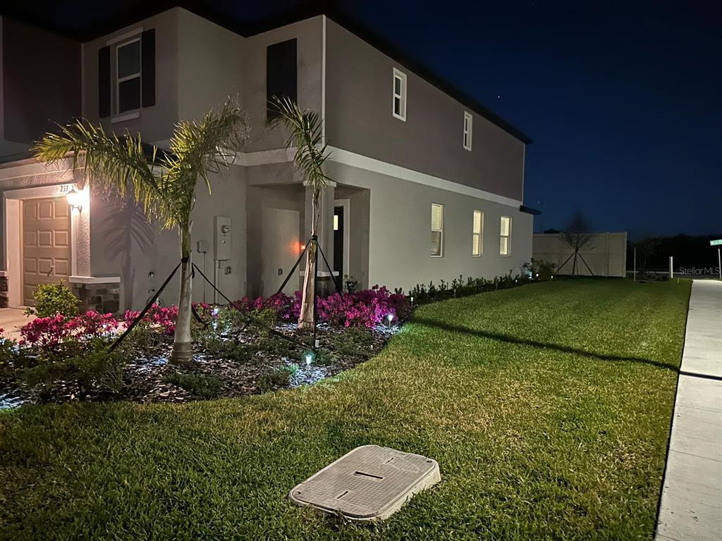 A two-story house exterior at night with palm trees, landscaping, and a lawn — 253 TULIP BANDED WAY, RUSKIN, FL