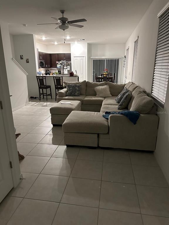 An open-concept living room with tile flooring, a large sectional sofa, and a kitchen beyond — 253 TULIP BANDED WAY, RUSKIN, FL