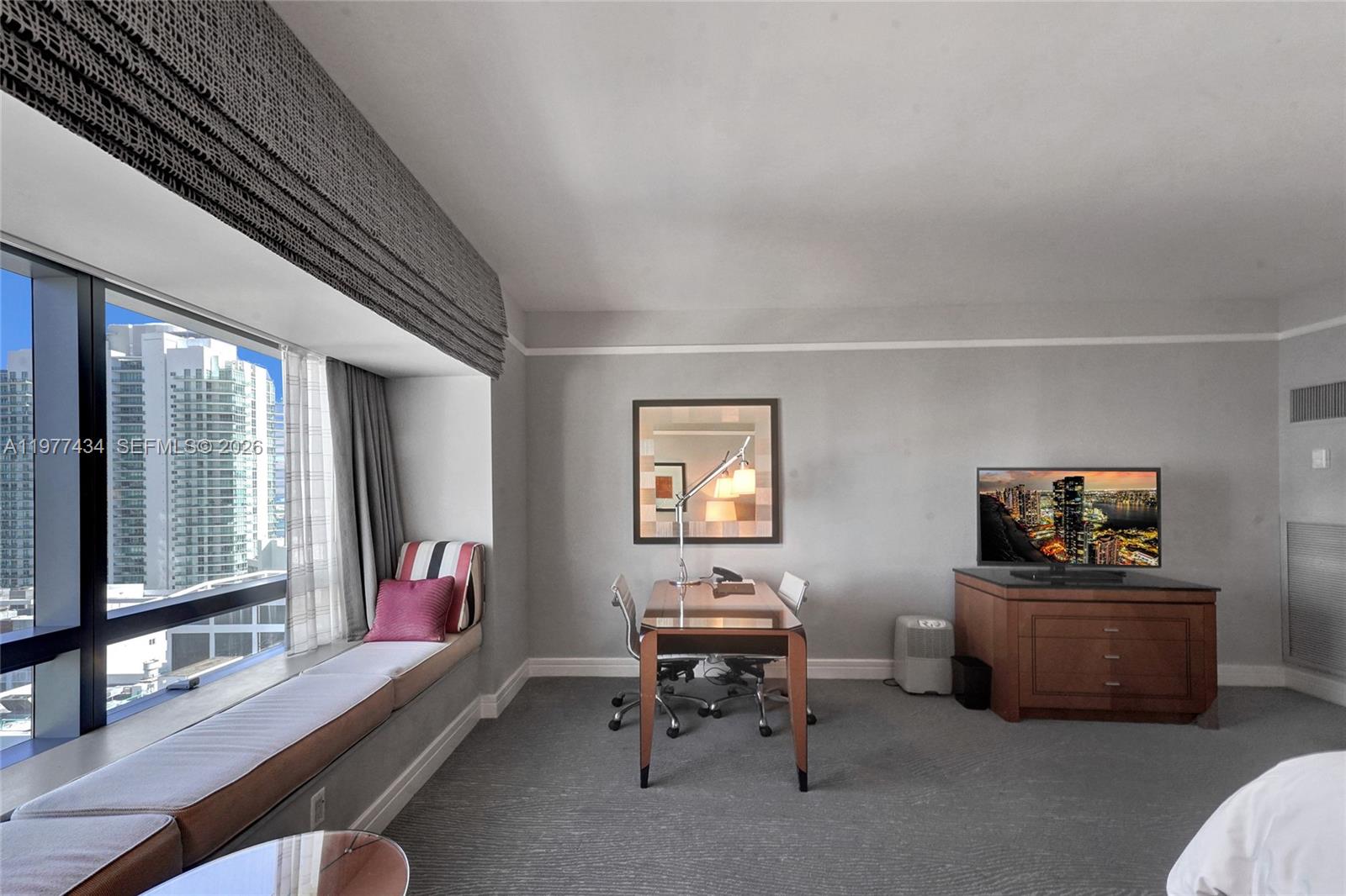 A bedroom features a window seat, a desk, a television console, and city views — 1435 Brickell Ave # 3308, Miami FL 33131, MIAMI, FL