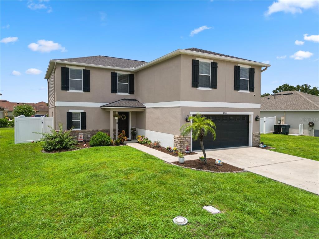 A two-story house with a beige stucco exterior, dark shutters, and a two-car garage — 4188 FESTIVAL POINTE BOULEVARD, MULBERRY, FL