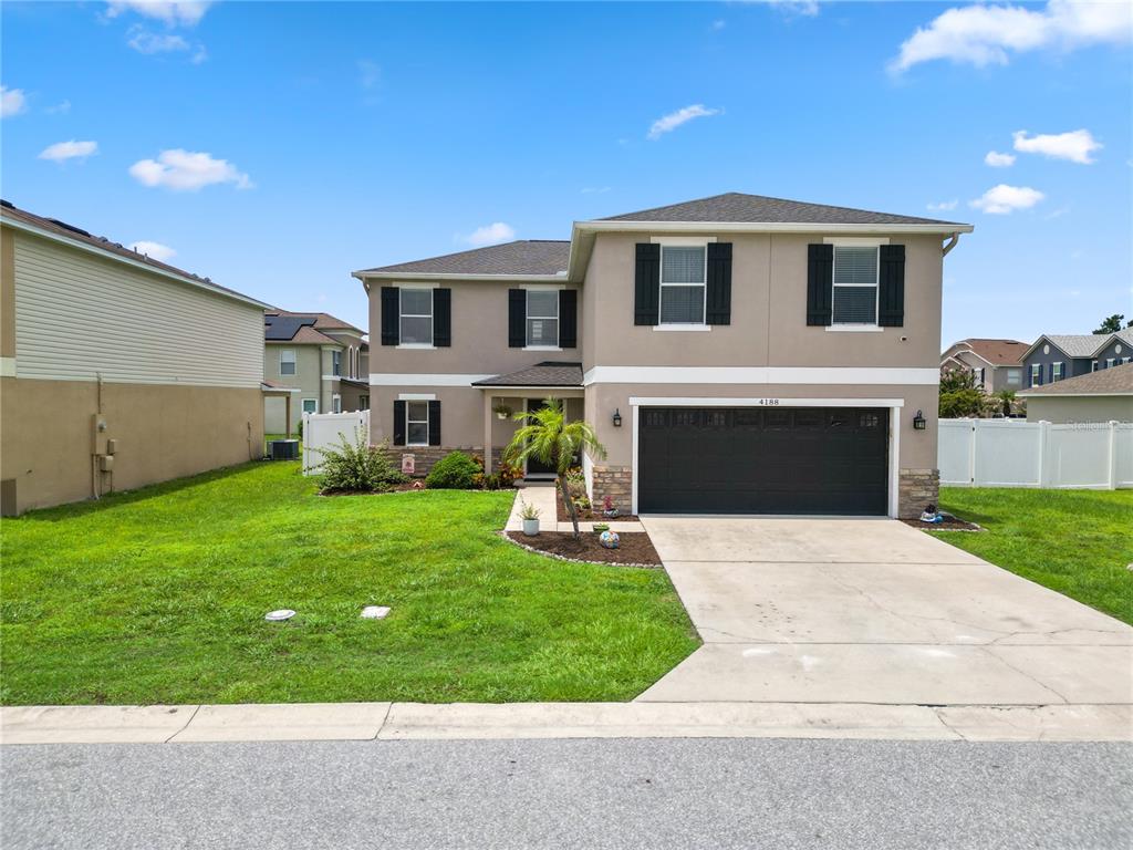 A two-story suburban house with a dark garage door and a concrete driveway — 4188 FESTIVAL POINTE BOULEVARD, MULBERRY, FL