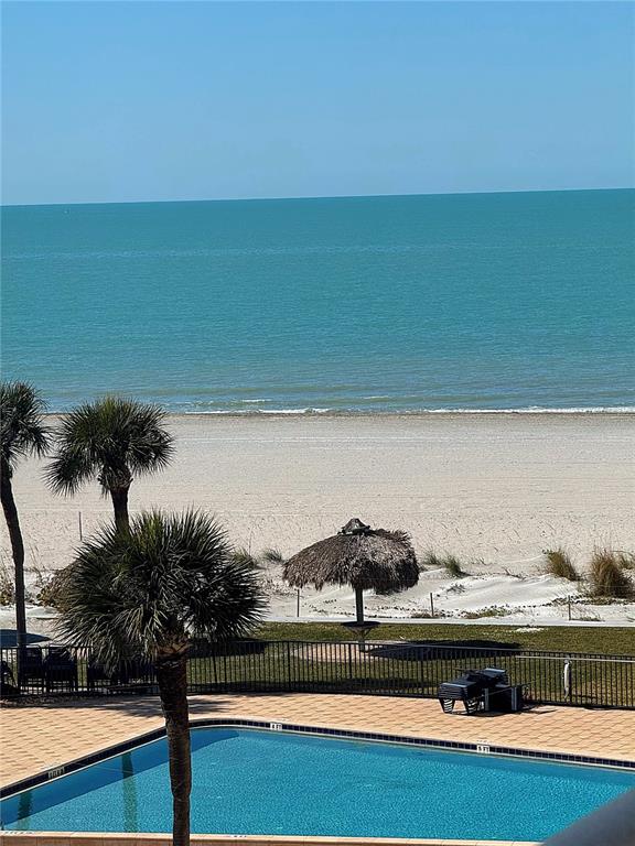 A swimming pool and palm trees overlook a sandy beach and the ocean — 1460 GULF BOULEVARD UNIT 411, CLEARWATER BEACH, FL