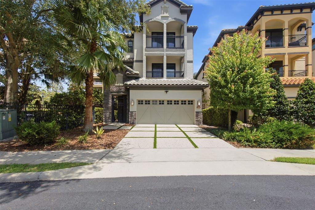 A three-story house with a two-car garage and a paved driveway with grass strips — 7689 TOSCANA BOULEVARD, ORLANDO, FL