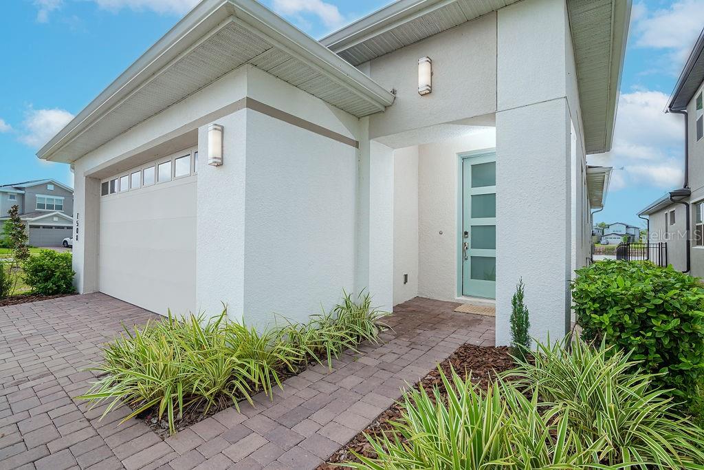 A modern one-story house exterior features a light blue front door and a paved driveway — 7508 WING SPAN WAY, ST CLOUD, FL