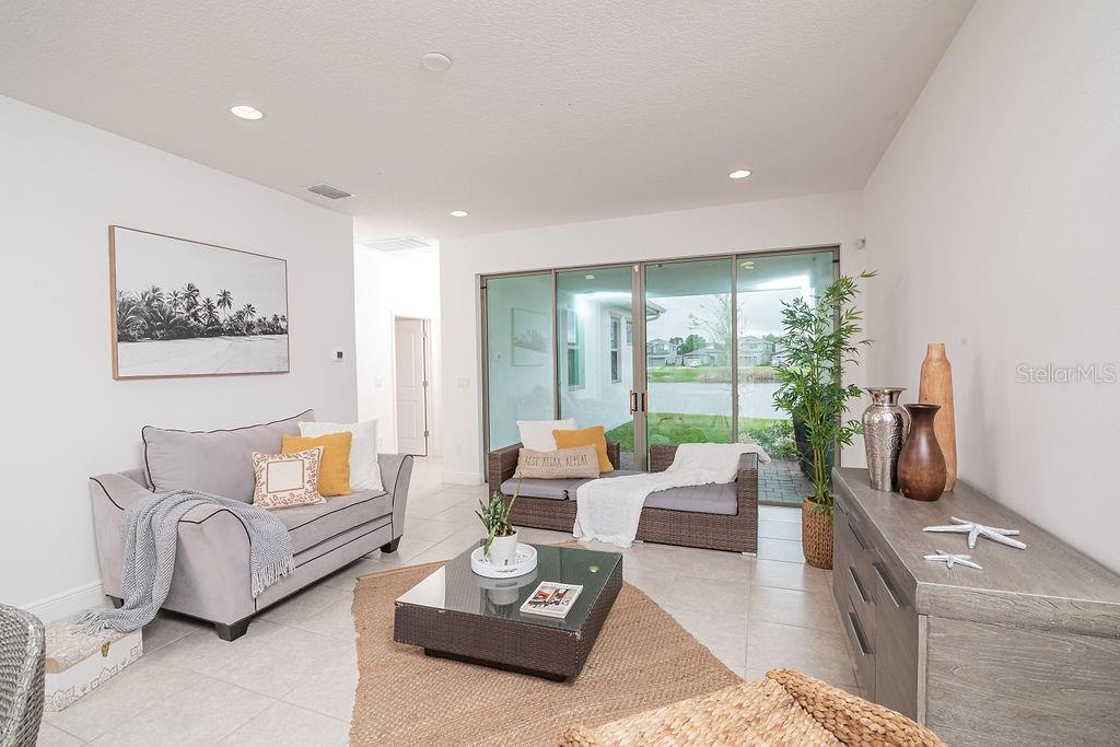 A living room features a grey sofa, wicker furniture, a coffee table, and sliding glass doors — 7508 WING SPAN WAY, ST CLOUD, FL