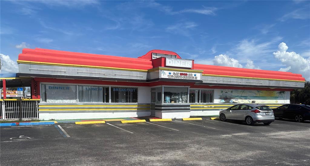 A red and yellow diner building sits in a parking lot under a blue sky — 1730 US HIGHWAY 19, HOLIDAY, FL