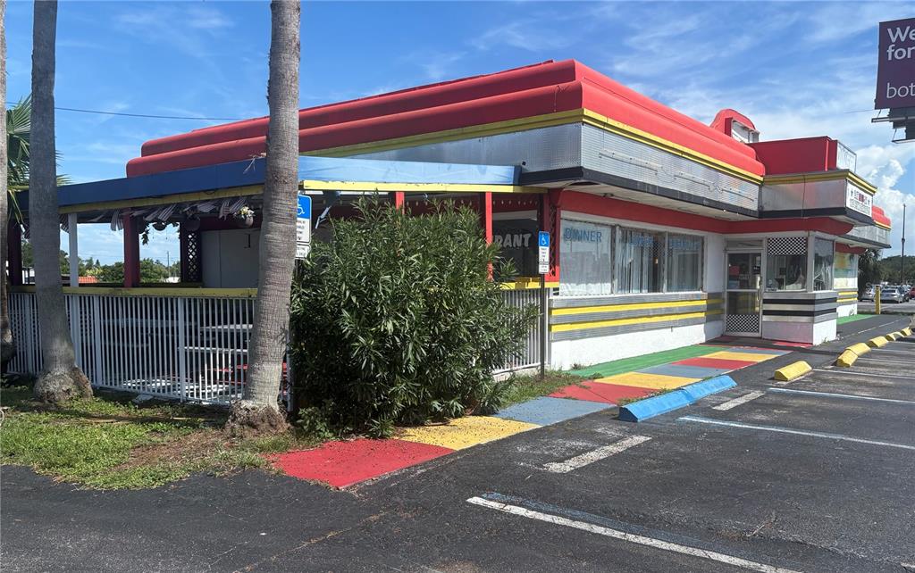 A retro-style diner building with a red roof, yellow accents, and an outdoor patio area — 1730 US HIGHWAY 19, HOLIDAY, FL