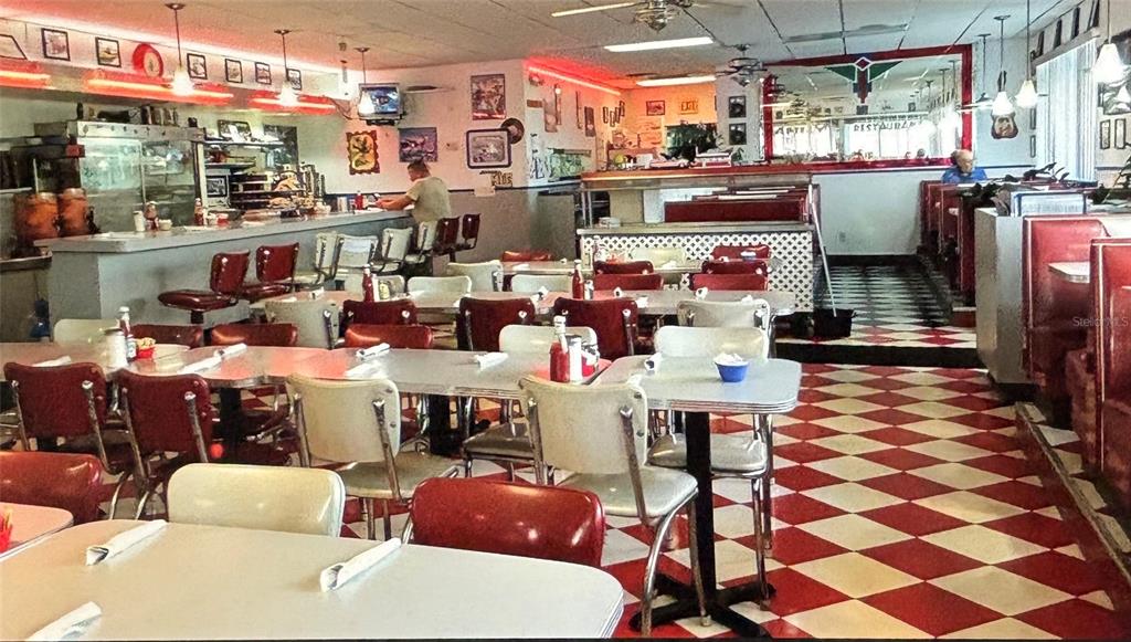 A retro-style diner features red and white checkered floors, booth seating, and a long counter — 1730 US HIGHWAY 19, HOLIDAY, FL