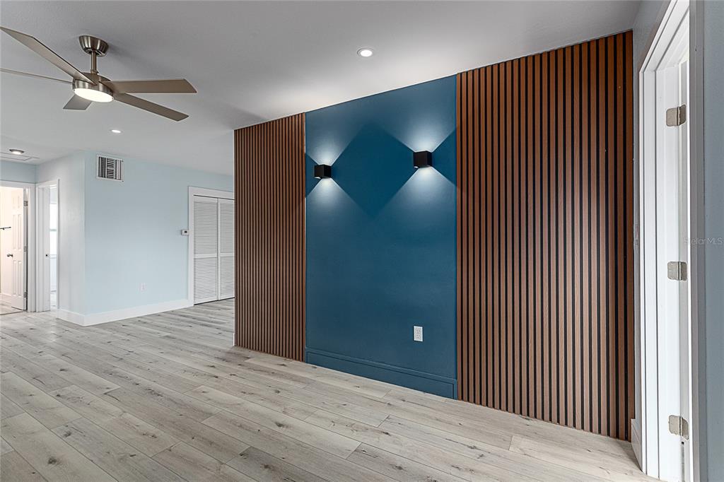 A room features a blue accent wall flanked by vertical wood slat panels and sconces — 3208 PINETREE STREET, PORT CHARLOTTE, FL