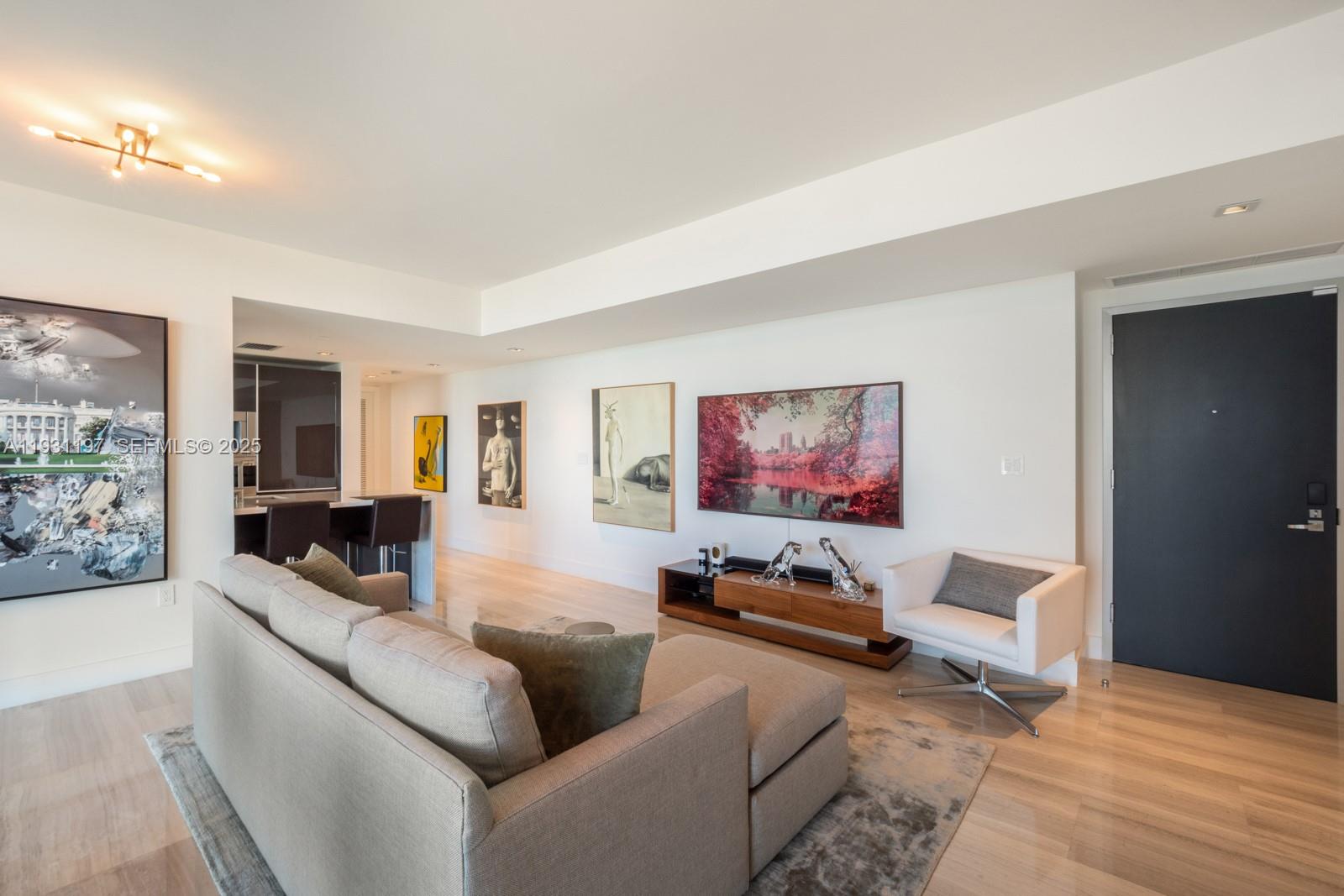 A modern living room features light wood floors, a sectional sofa, and several framed artworks — 1451 Brickell Ave # 2405, Miami FL 33131, MIAMI, FL