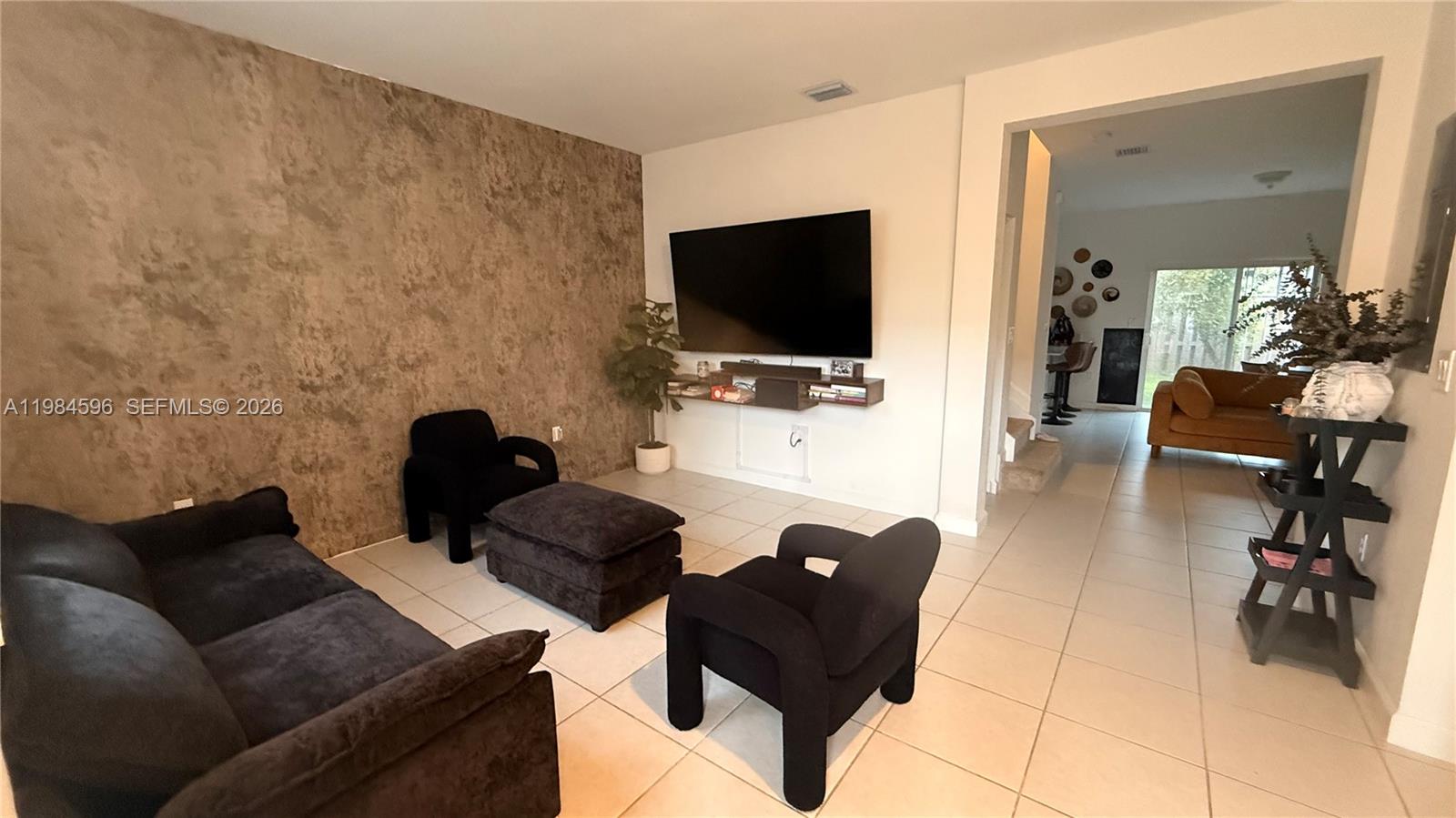 A living room features a textured accent wall, black furniture, and tile flooring — 12383 NW 23rd Ct, Miami FL 33167, MIAMI, FL