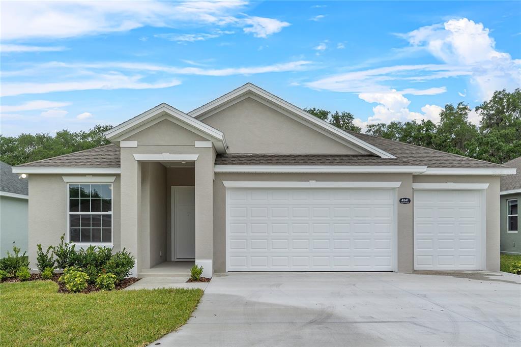 A single-story house with a beige stucco exterior, a two-car garage, and a front porch — 4541 FAIRWAY OAKS DRIVE, MULBERRY, FL