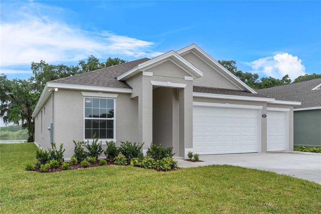 A single-story house with a gray stucco exterior, a two-car garage, and a front lawn — 4541 FAIRWAY OAKS DRIVE, MULBERRY, FL