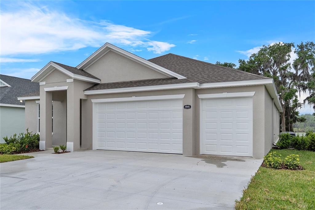 A beige single-story house features a three-car garage and a concrete driveway — 4541 FAIRWAY OAKS DRIVE, MULBERRY, FL