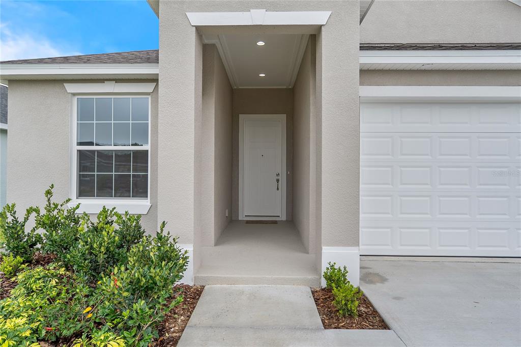 The exterior of a house features a white front door, a window, and a garage — 4541 FAIRWAY OAKS DRIVE, MULBERRY, FL