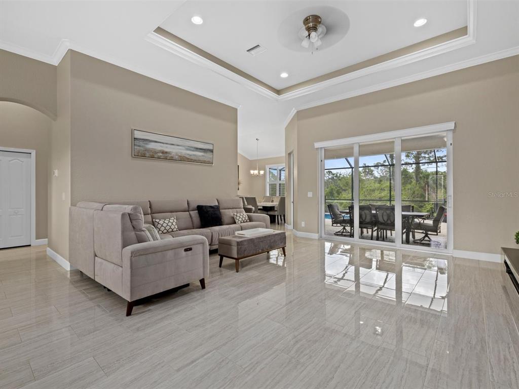 A living room with light tile floors, a sectional sofa, and sliding glass doors — 340 MCCABE STREET, PORT CHARLOTTE, FL