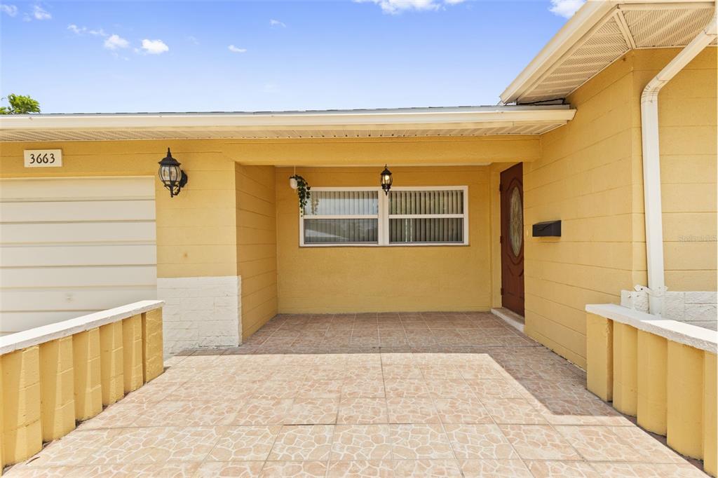 A yellow house exterior features a tiled front porch, a garage, and a front door — 3663 22ND AVENUE N, ST PETERSBURG, FL