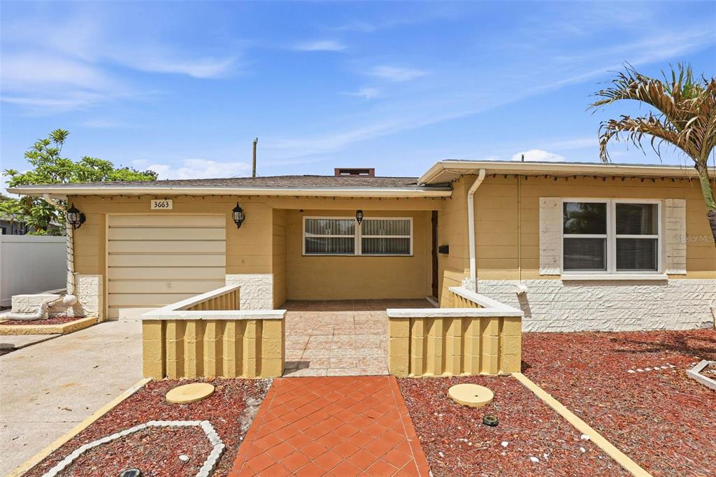 A single-story house with a tan exterior, a garage, and a front patio area — 3663 22ND AVENUE N, ST PETERSBURG, FL